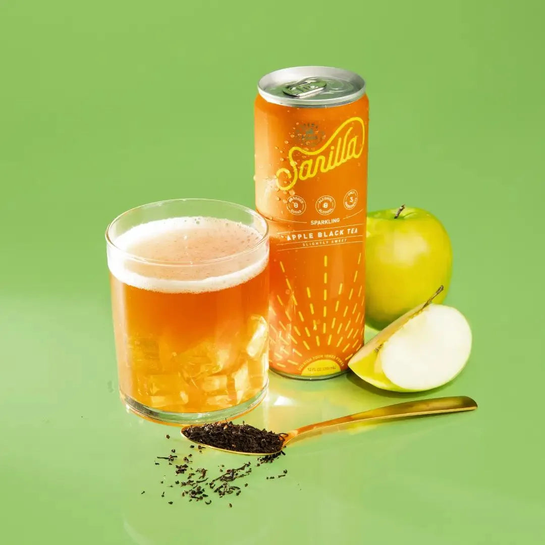 a can of apple next to a full glass and apples