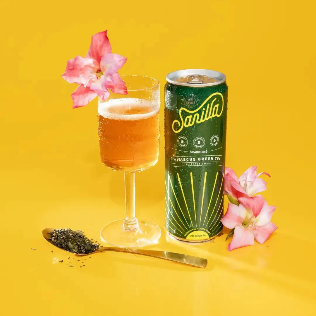 a can of hibiscus next to a full glass and hibiscus flowers