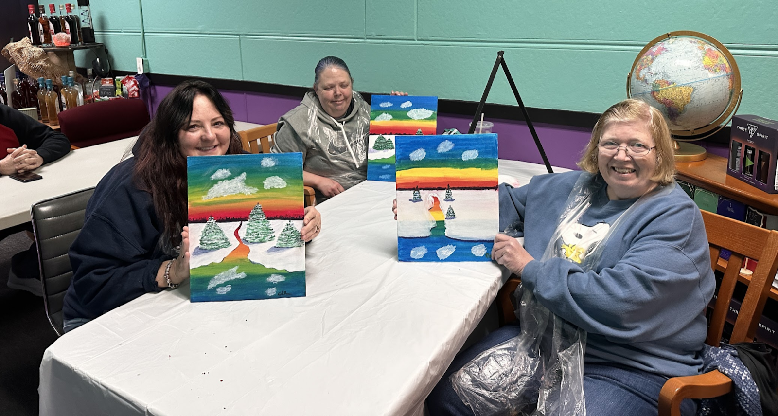 customers posing with their paintings from the sip & Paint