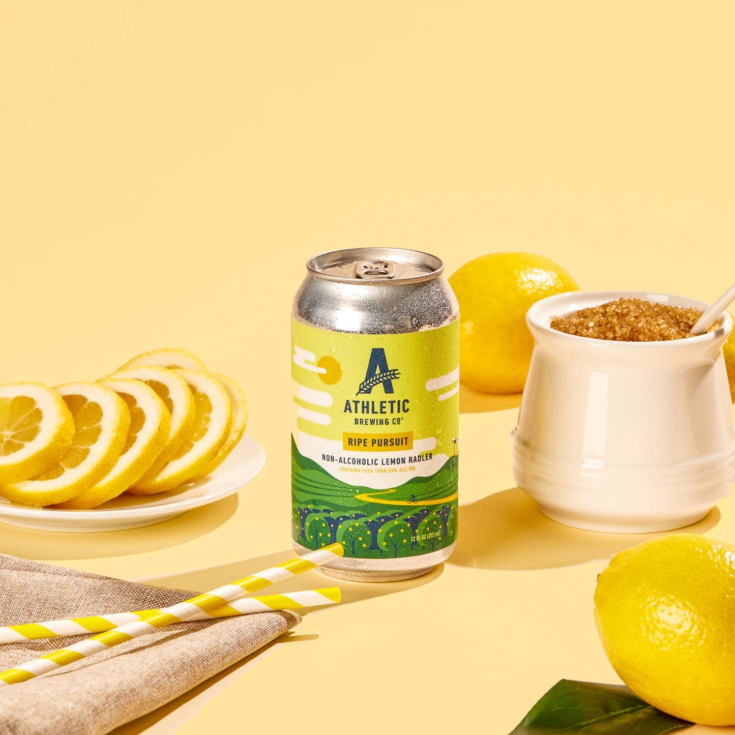 te ripe pursuit can surrounded by lemons, lemon slices, lemon seeds and yellow straws on a pale yellow background