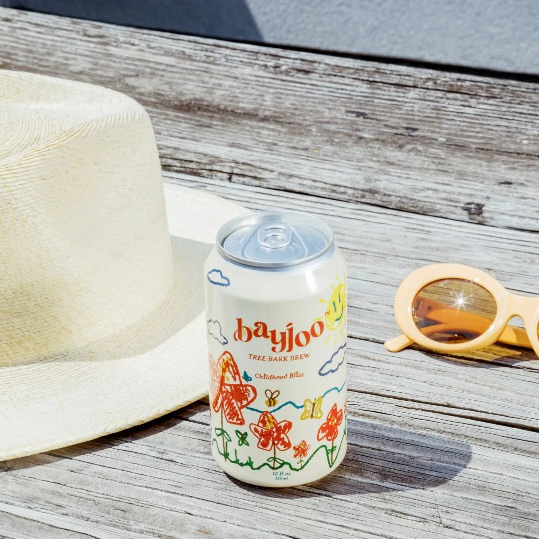 a can of bliss on a wooden table with sunglasses and a sun hat