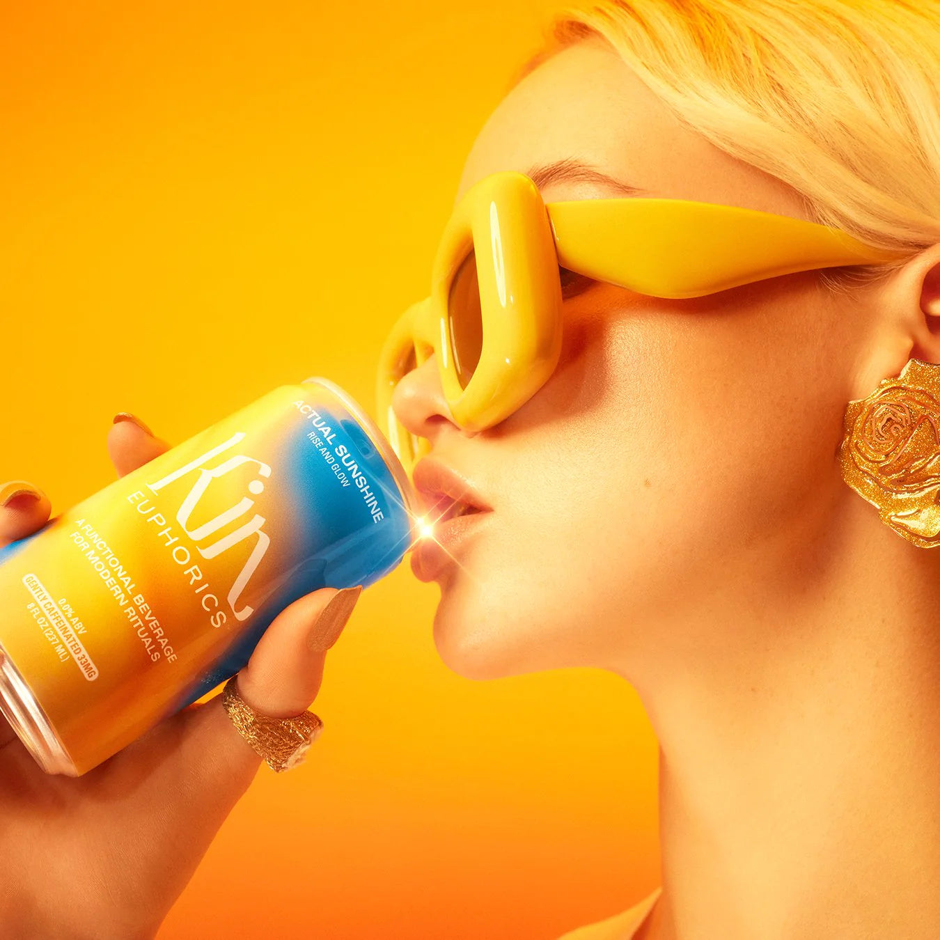 a blonde woman drinking get your glow on an orange background
