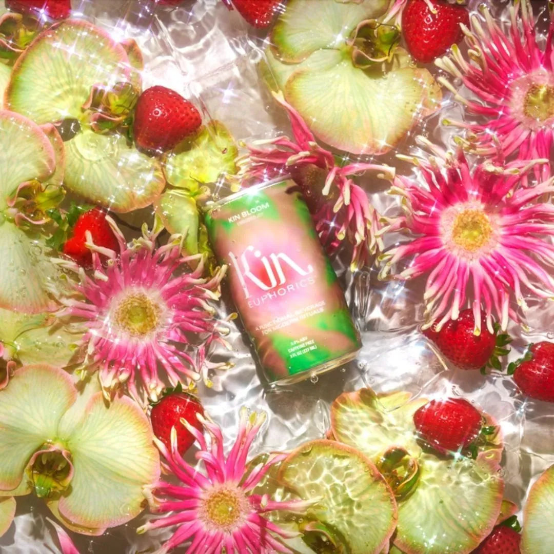 a can of kin bloom surrounded by yellow orchids, pink flowers and strawberries