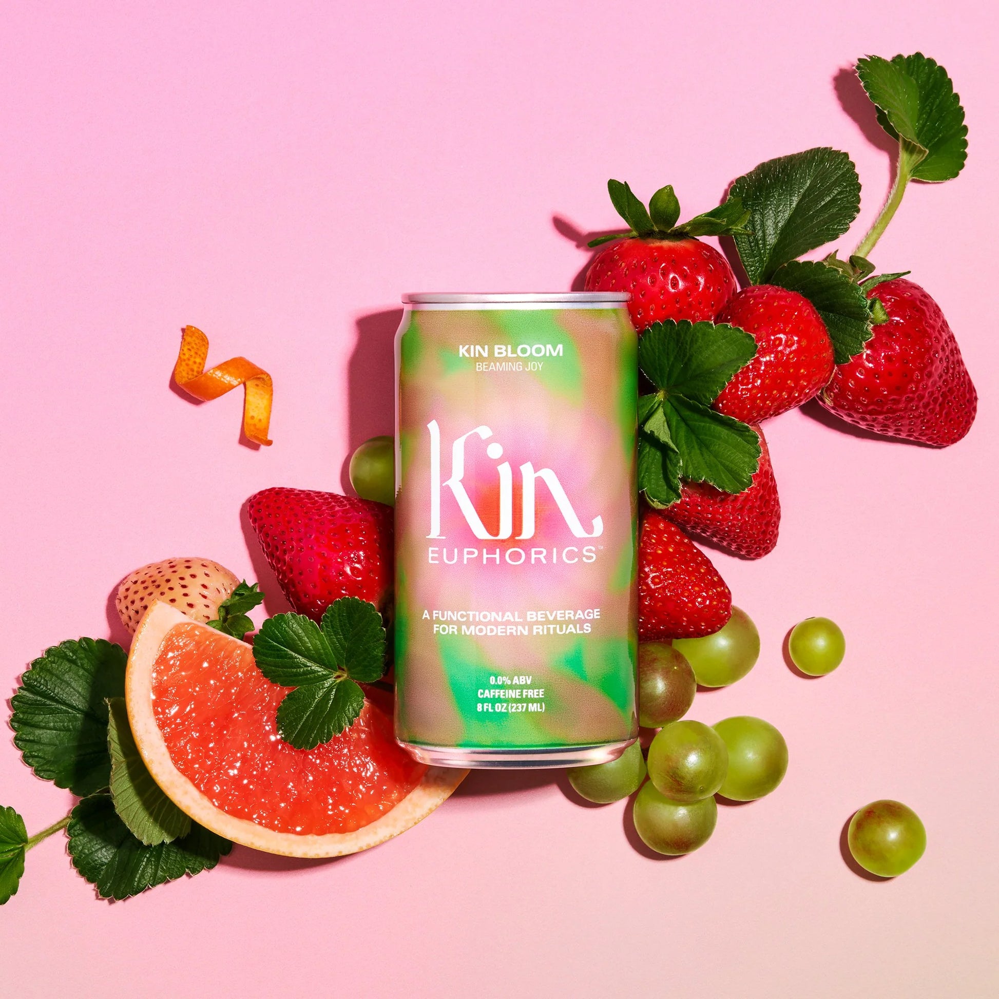 a can of kin bloom with a variety of fruit on a pink background