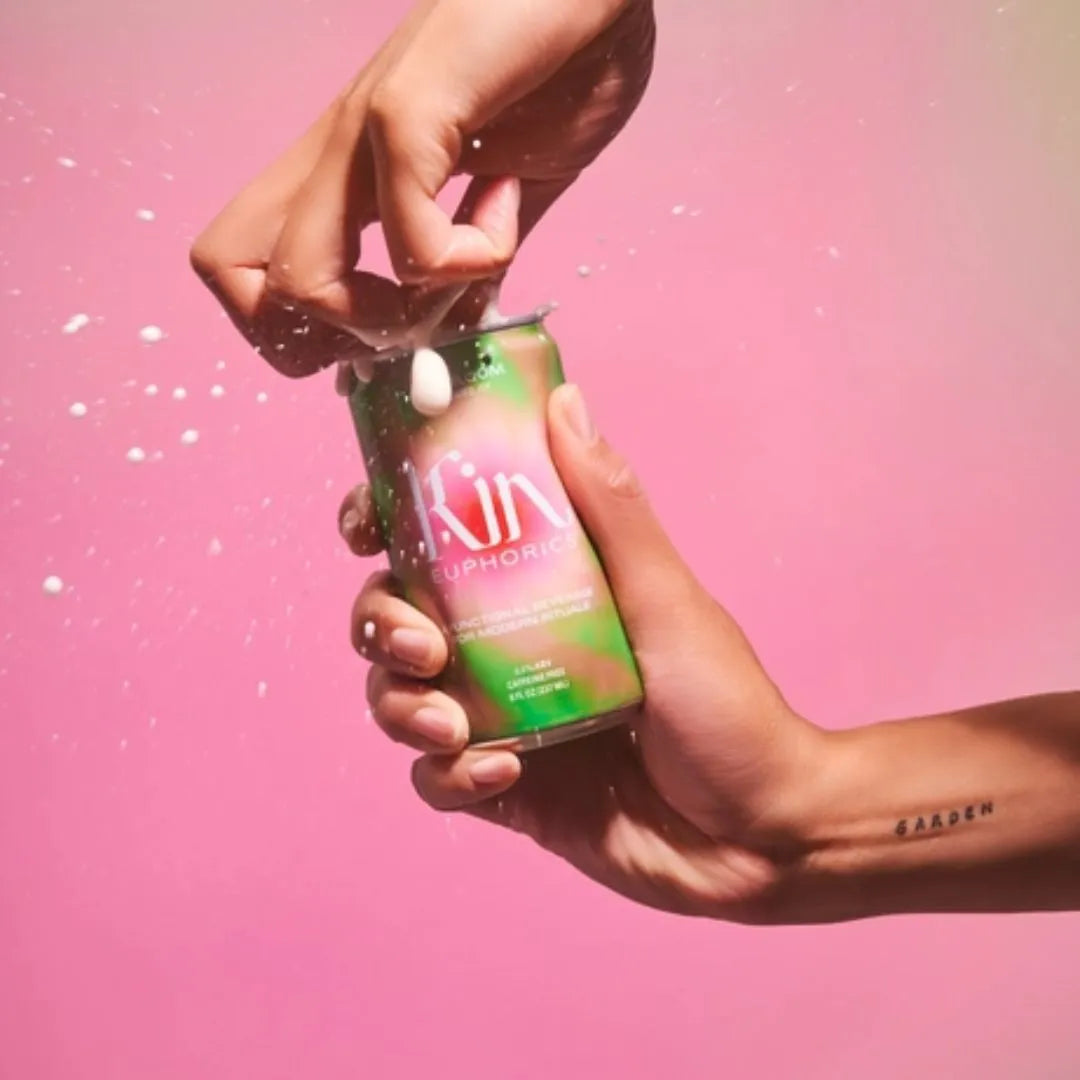 a person opening a can of kin bloom in front of a pink background