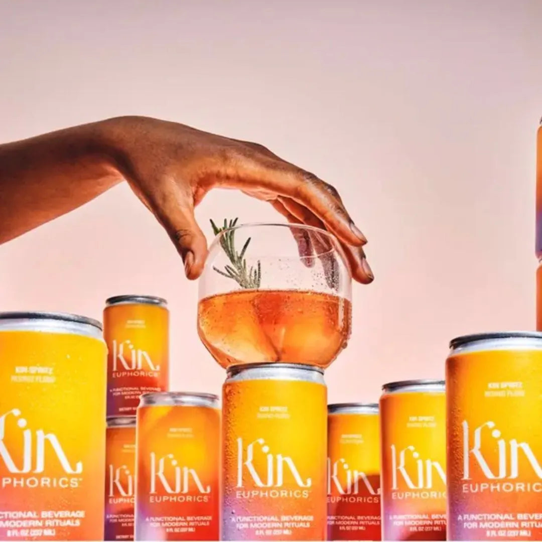 cans of kin spritz lined up with a glass of kin spritz on top