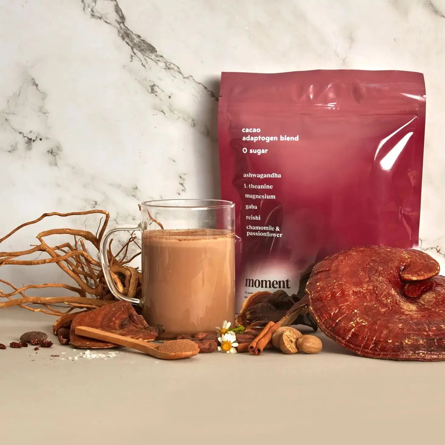 a pacage of moment's cacao adaptogen blend along with a full glass and a variety of herbs