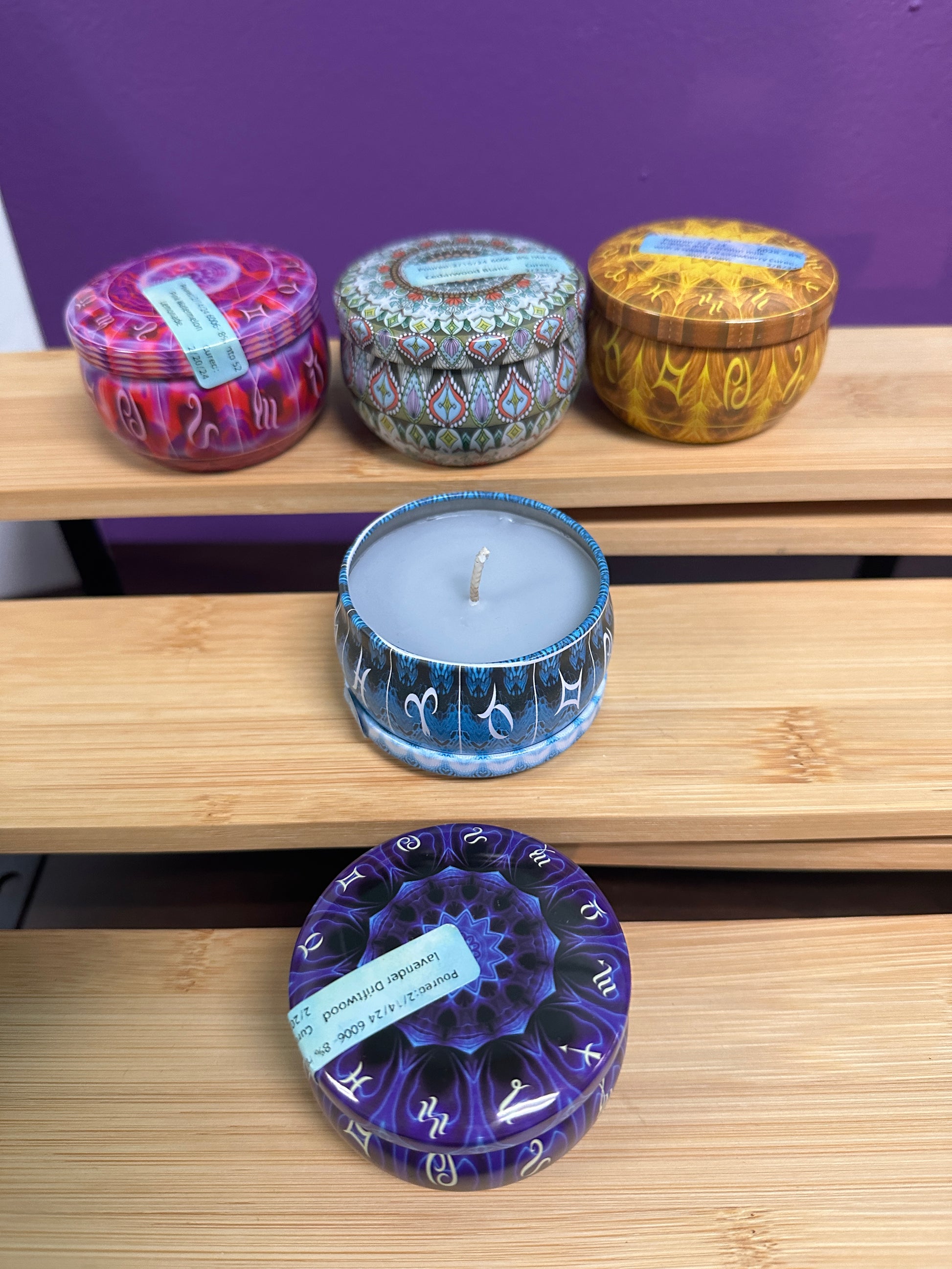 a display of 5 small candles in patterned tins. each color has a different fragrence