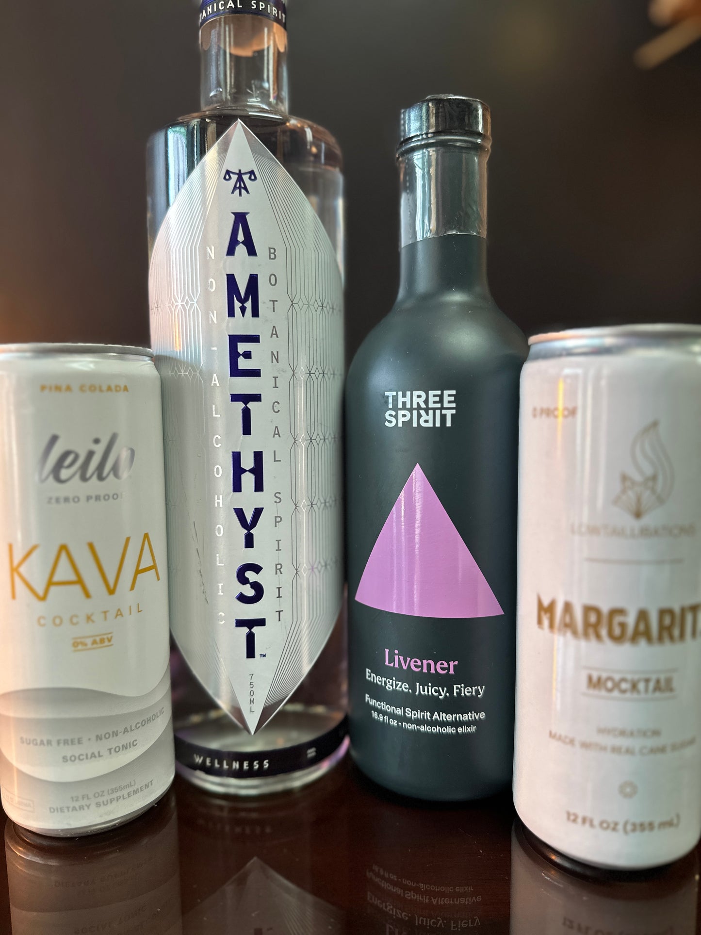 four drinks dispalyed next to eachother, the edge drinks are cans while the center drinks are in bottles